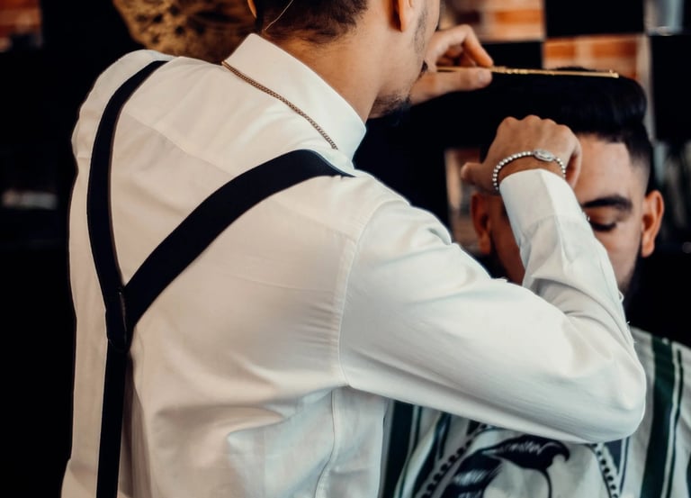 a man in a hat and suspender tie dyes a man's hair