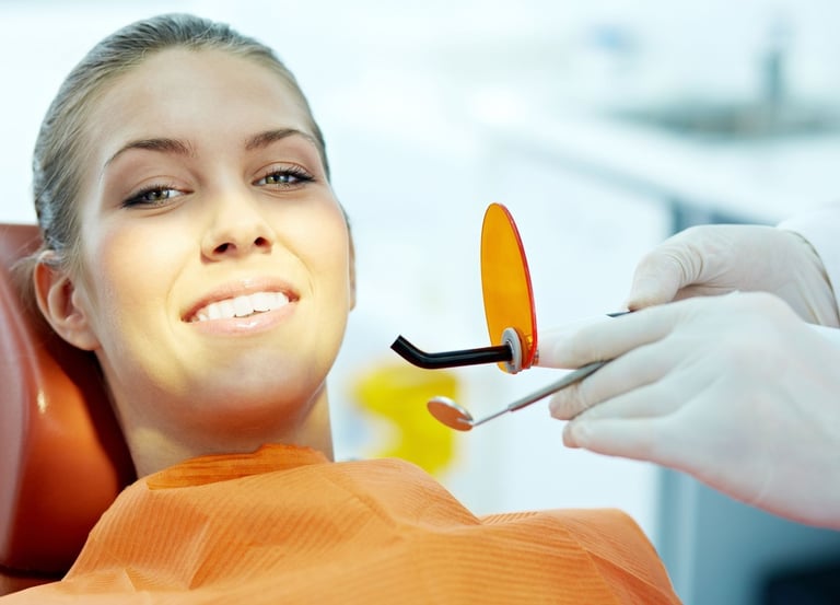 A smiling woman as a dentist holds instruments nearby.