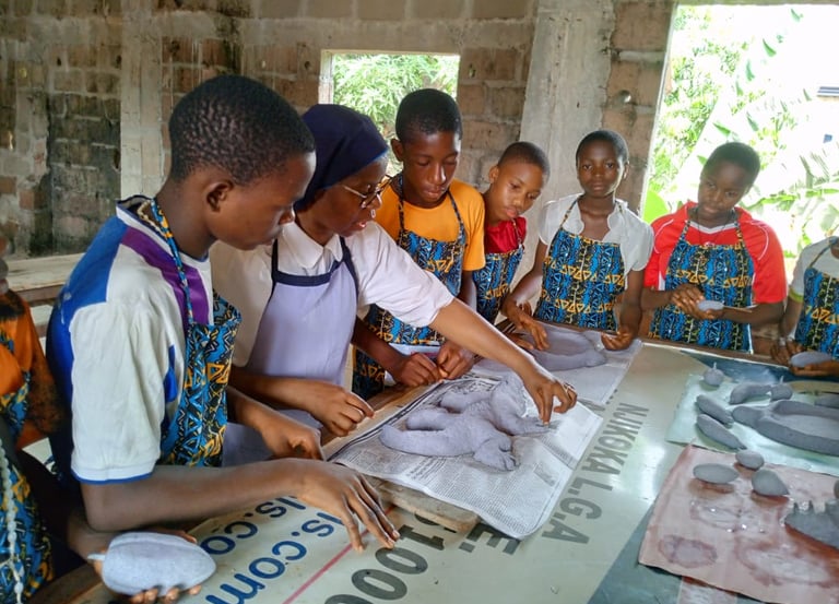 Students and teacher crafting paper sculptures during an art workshop in an African classroom.