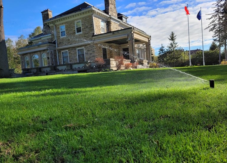 Large estate featuring professional lawn care and active sprinkler system for a lush landscape