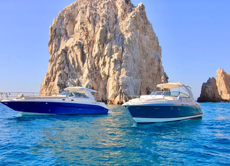 Luxury motor yachts cruising past the iconic El Arco rock formation in Cabo San Lucas.