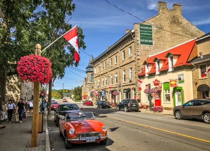 Red vintage MG convertible parked on a historic street in Merrickville, Ontario, near the Baldachin Inn.