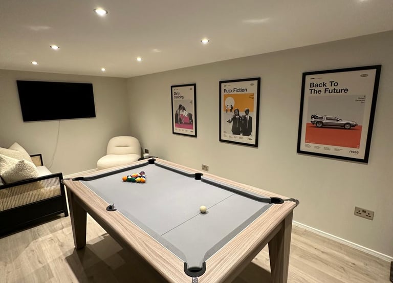 Modern game room featuring a luxury grey pool table and framed movie posters on the wall.