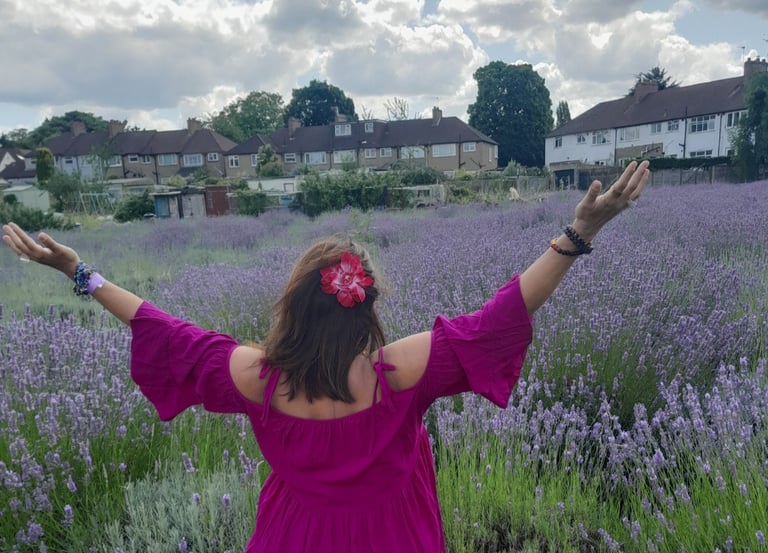 Image of the back of Sheila Cristina in a lavender field in London.  In the distance is houses. 