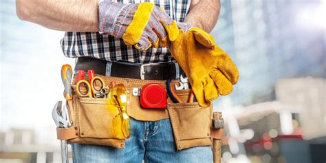 Handyman with tool belt putting on gloves ready to work