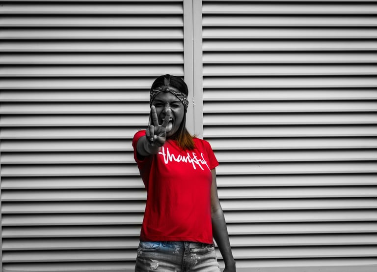 grayscale photo of a thankful college student in a red shirt doing the victory sign