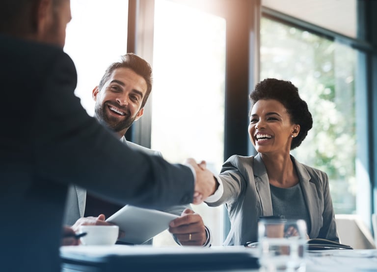 Smiling professionals shaking hands in a business meeting, symbolizing successful career transitions