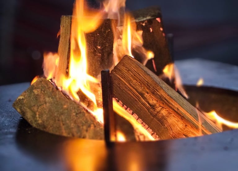 A warm outdoor fire pit with burning wood logs and glowing orange flames.