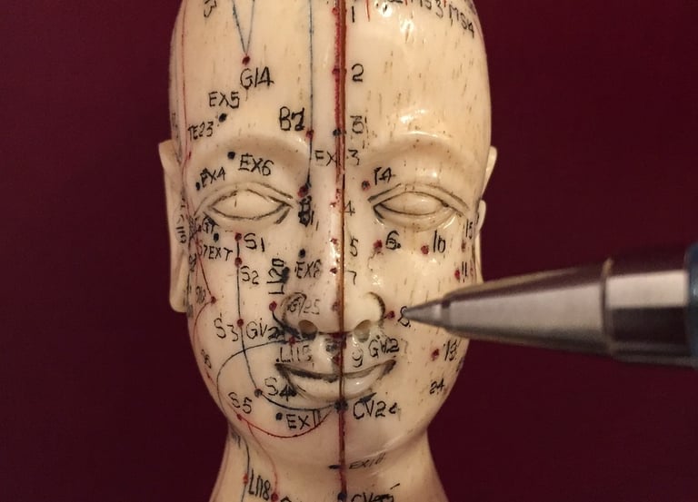 eine asiatische Kopfstatue mit aufgemalten Akupunkturpunkten