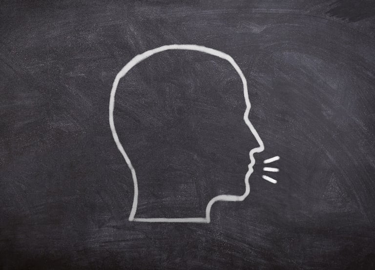 Un visage dessiné de profil sur un tableau noir, avec une bulle de dialogue