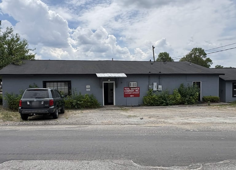Exterior view of Tool Service Company Inc. storefront with customer entrance sign and parked SUV.