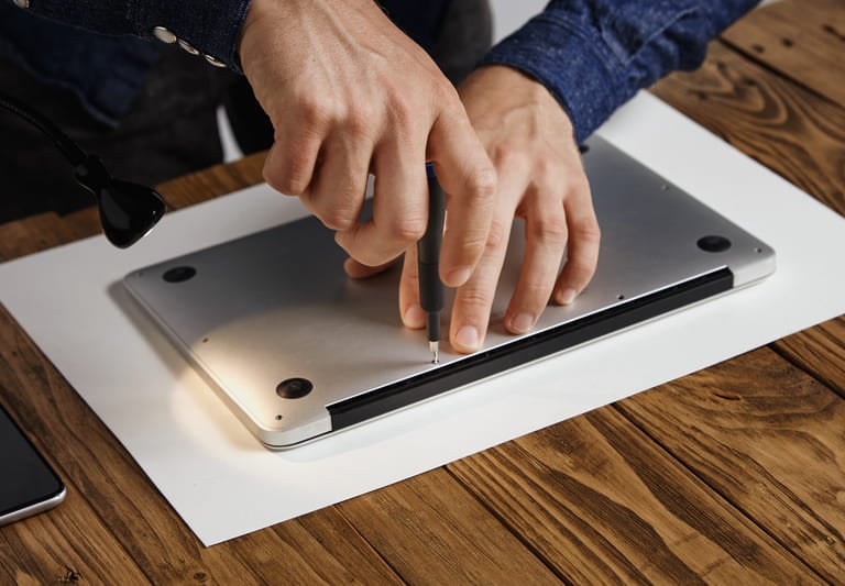 Técnico utilizando un destornillador para realizar una reparación de laptop y mantenimiento