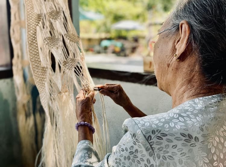 mujer mayor tejiendo adorno de macramé en un taller al aire libre
