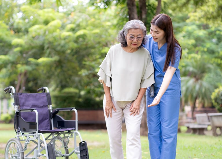 A female caregiver helping a female patient walk