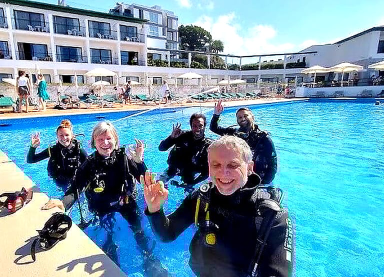 Happy group giving OK sign during try scuba diving experience at Quinta da Penha de França Mar pool, Madeira