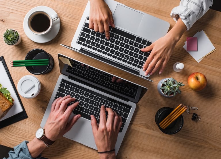 a man and woman working on laptops at a desk
