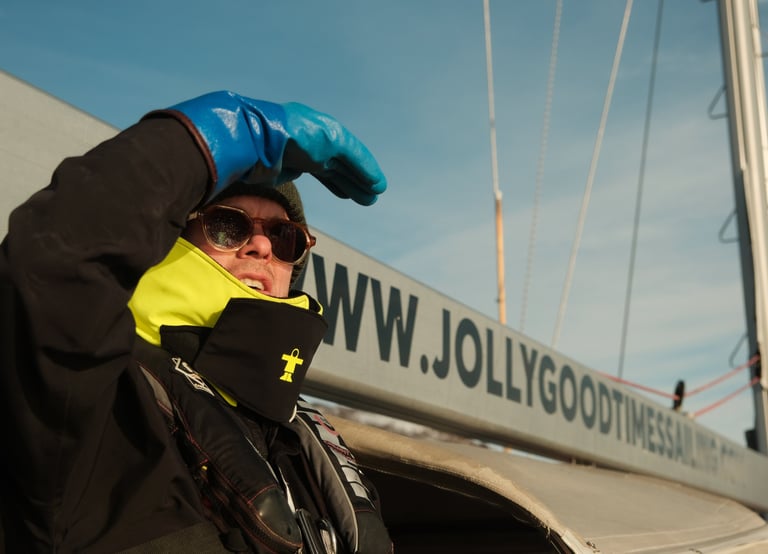 Ulrik på seilbåt skjermer øynene mot sola, vind og sjø i bakgrunnen.