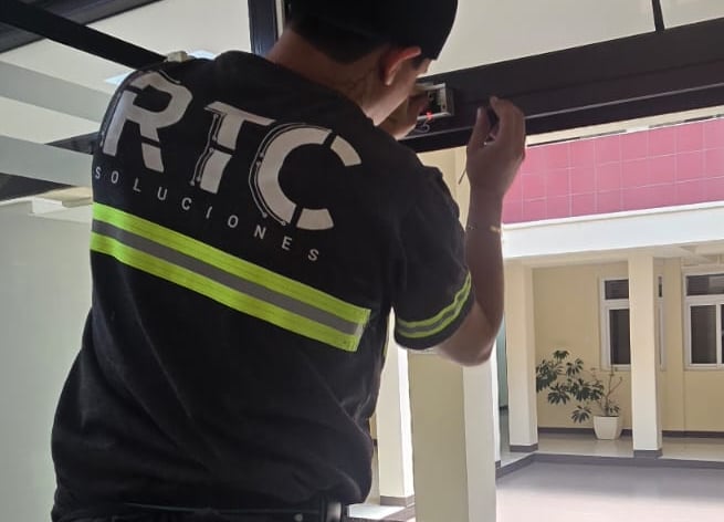 Técnico instalando sensor o botón de acceso en marco de puerta.
