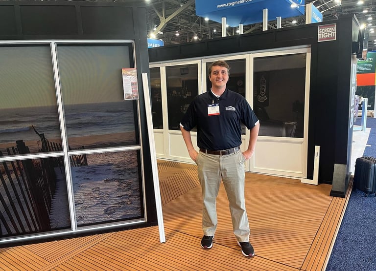 Representative showcasing screen porch solutions at a trade show booth.