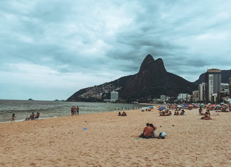 a beach with people sitting on the sand, Ipanema, Rio de Janeiro, Brazil