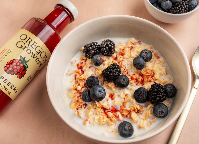 a bowl of cereal with berries and a bottle of syrup