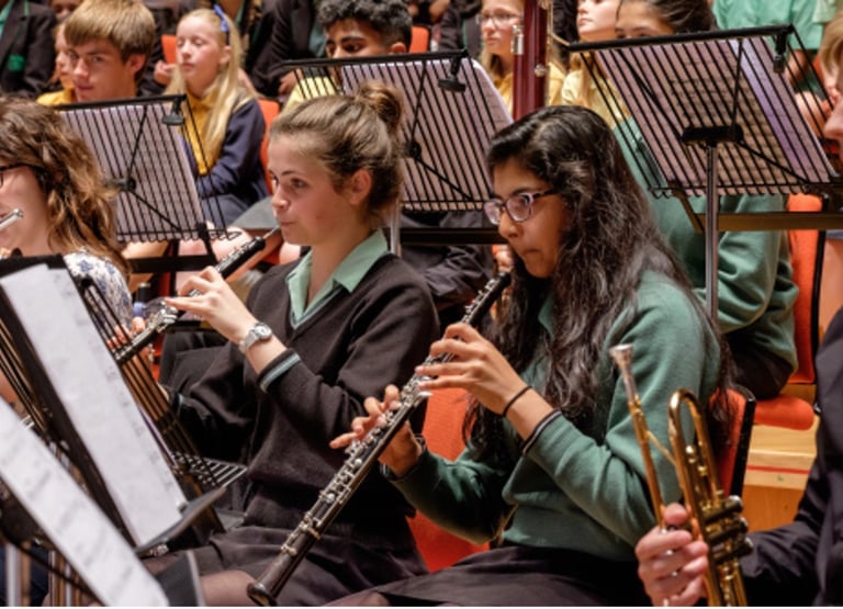 Students in a youth orchestra performing with oboes and flutes during a performance of Romany Wood