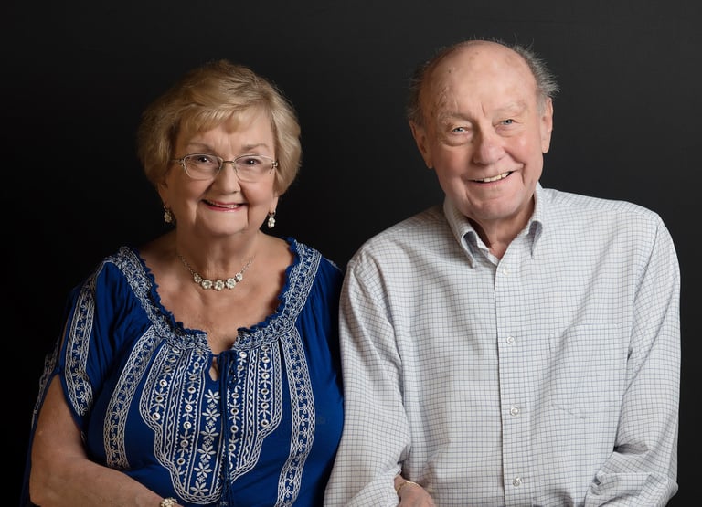 a man and woman sitting next to each other smiling holding hands