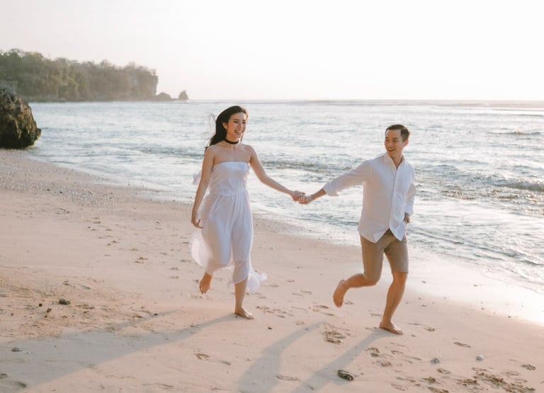 Couple running on the beach after a proposal photography session at Anantara Uluwatu Bali Resort.