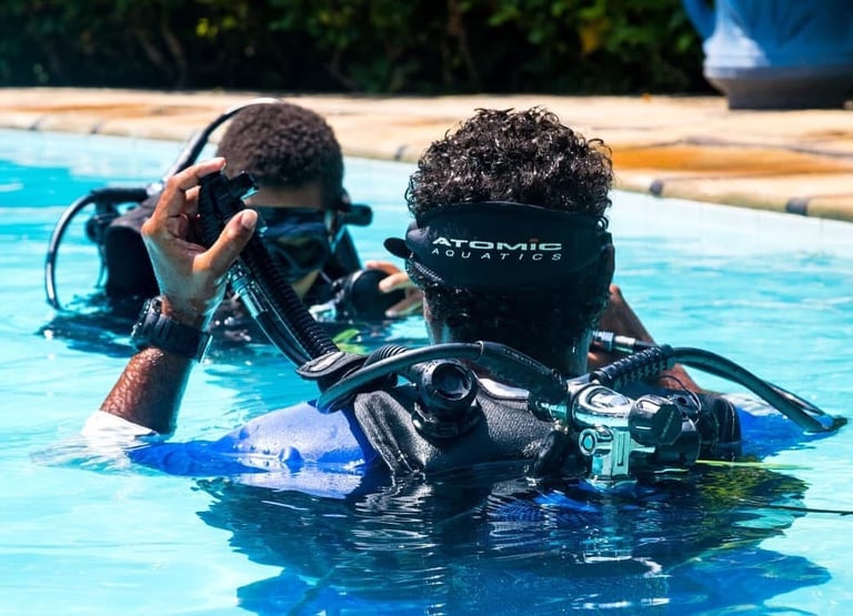 Scuba divers practicing breathing techniques with diving gear in a clear swimming pool.