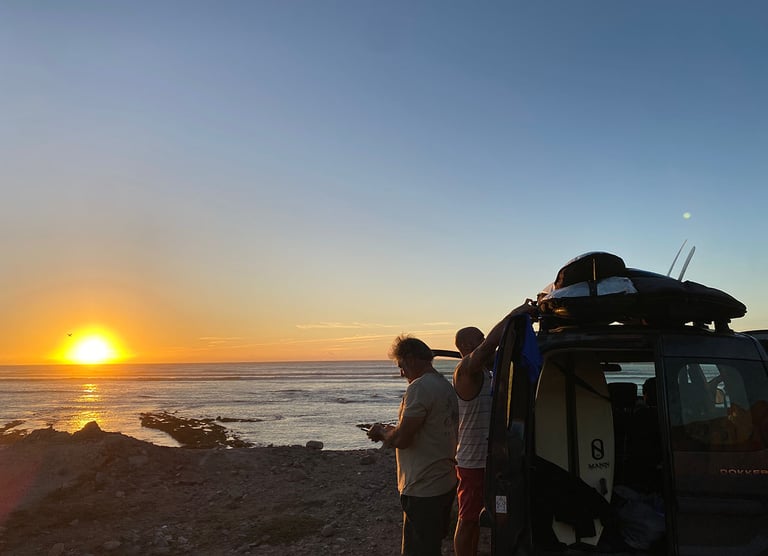 a man standing next to a car with a surfboard on it