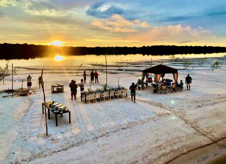 Jantar servido em uma praia de rio com o por do sol
