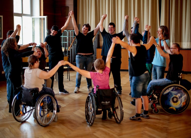 Menschen mit und ohne Behinderung bilden einen Kreis und halten lachend die Hände in die Luft