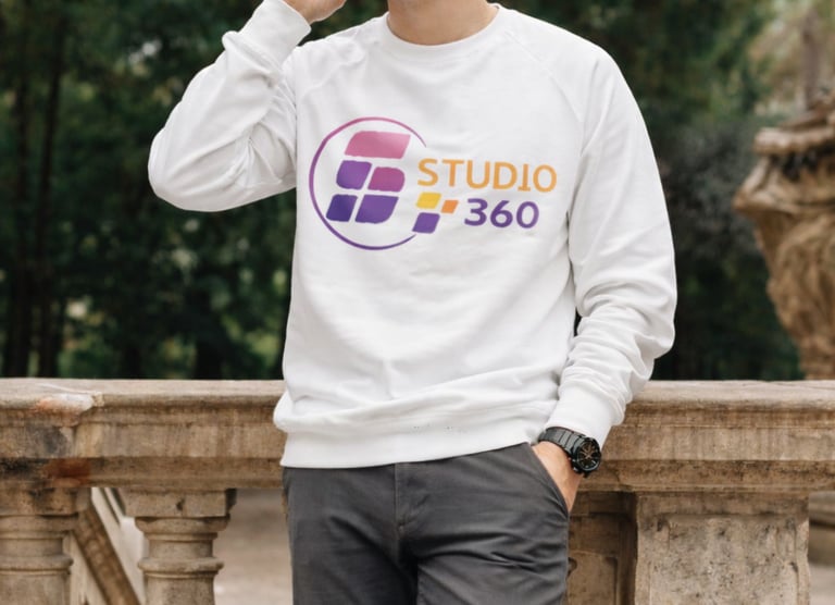 Smiling man in a Studio 360 branded white sweatshirt talking on his phone outdoors.