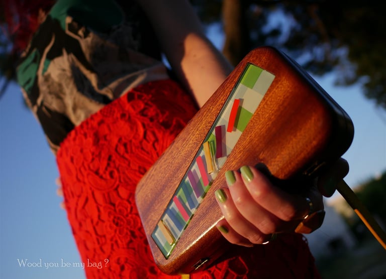 a woman holding a wooden clutch decorated with colorful glass tile