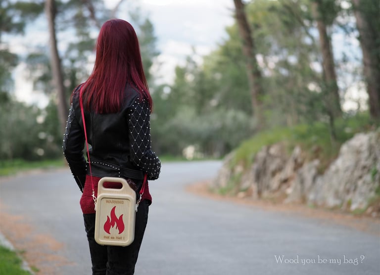 a woman with red hair and a wooden handbag walking down a road