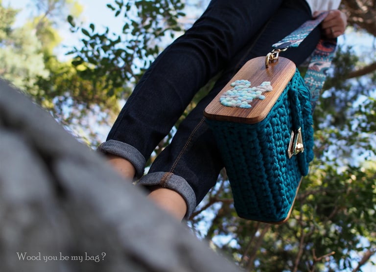 a person standing on a rock wall with a wooden handbag