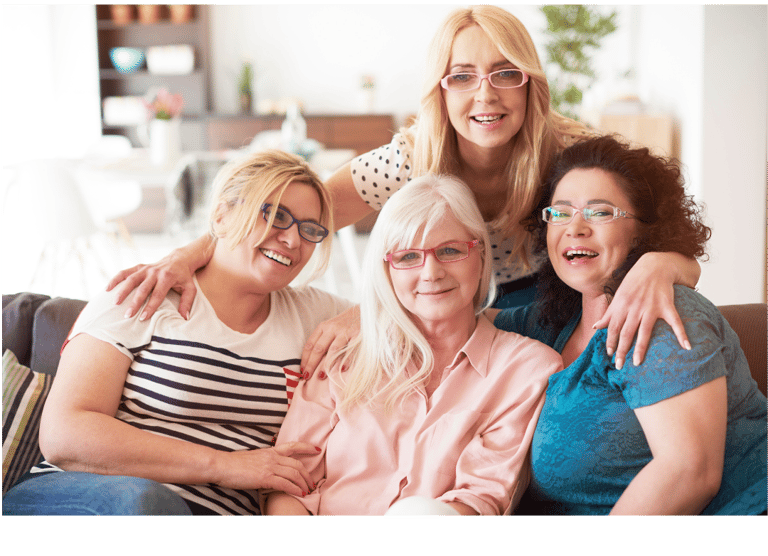 a group of women sitting on a couch wearing eyeglasses and smiling