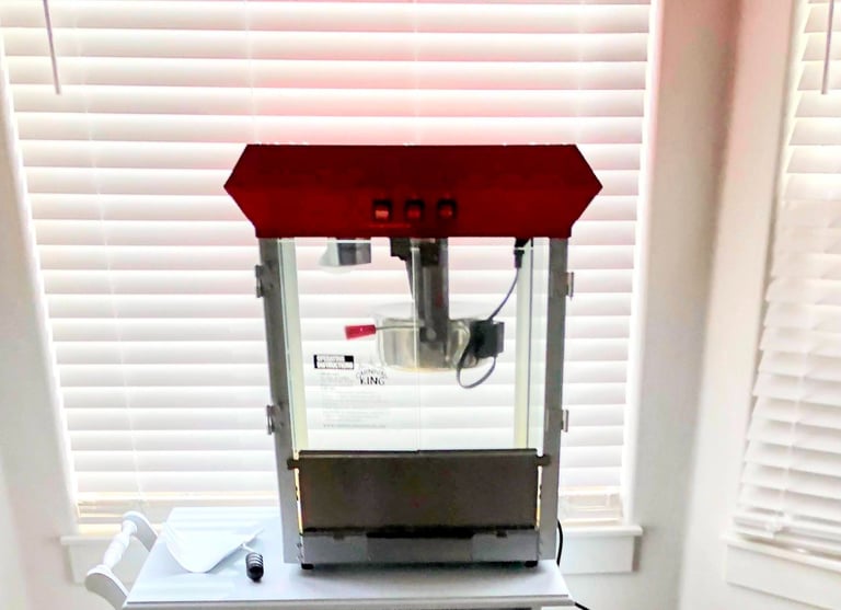 a popcorn machine and popcorn scoop sitting on a white table