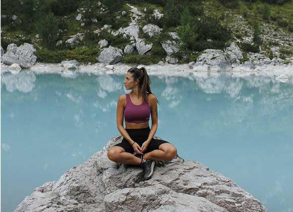 Magui sentada en una piedra sobre un lago