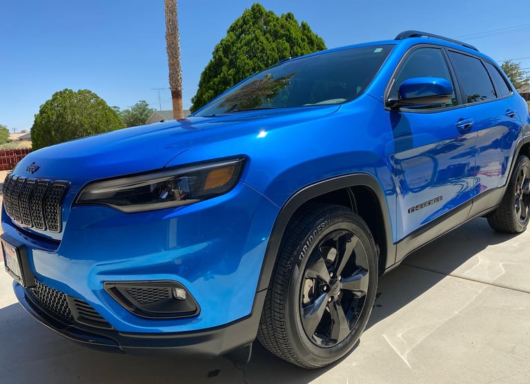 a newly detailed blue jeep parked in front of a palm tree