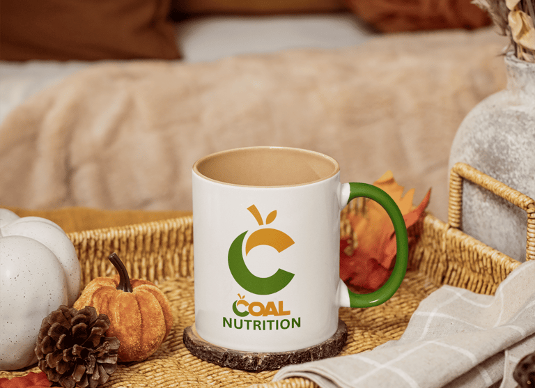 Coal Nutrition branded coffee mug on a wicker tray with autumn pumpkins and pinecones.