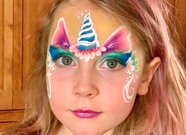 Girl with pretty unicorn face painting. 