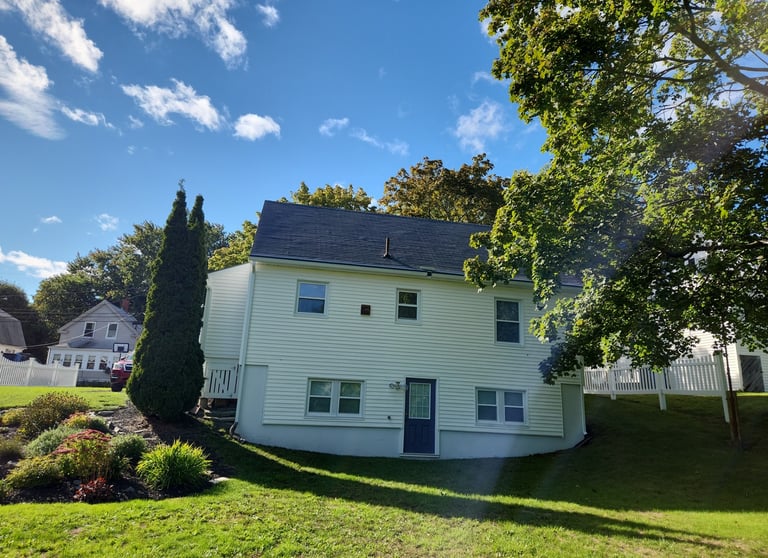 a house with a white house with a blue sky and clouds