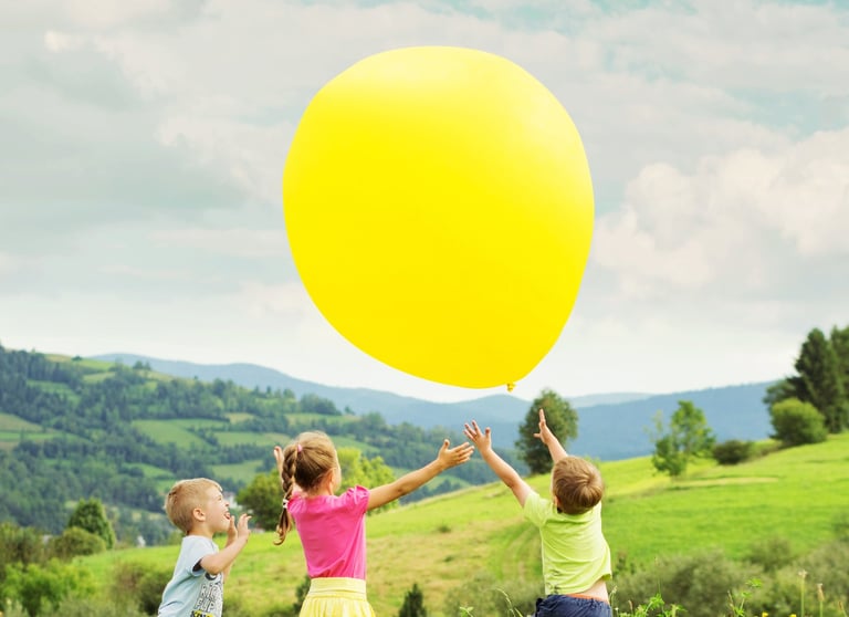 two children playing with a large yellow balloon