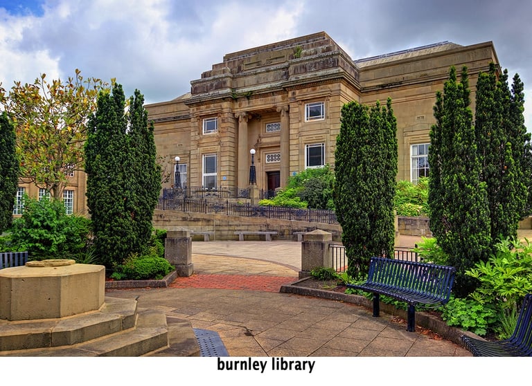 a bench with burnley library building in the background