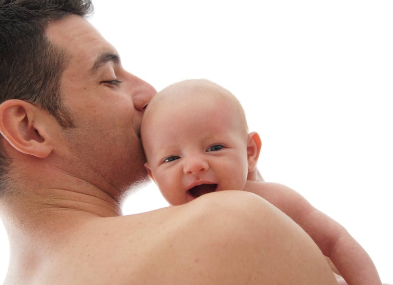 Bébé qui sourit avec la tête qui dépasse de l'épaule de son père lors d'une séance photo high-key