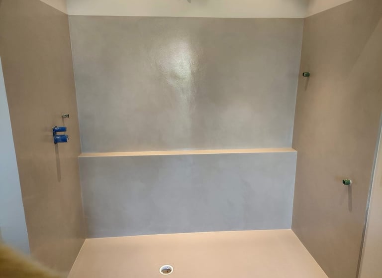 Modern walk-in shower with seamless waterproof microcement walls and a minimalist gray finish.