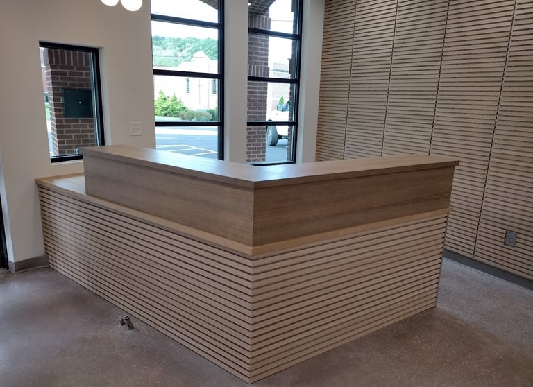 Custom wood reception desk with slat wall paneling in a modern office lobby.