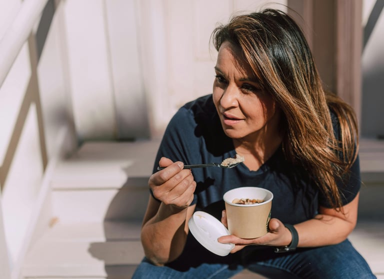 she is eating healthy snack with spoon at the office stairs during lunch while relaxing
