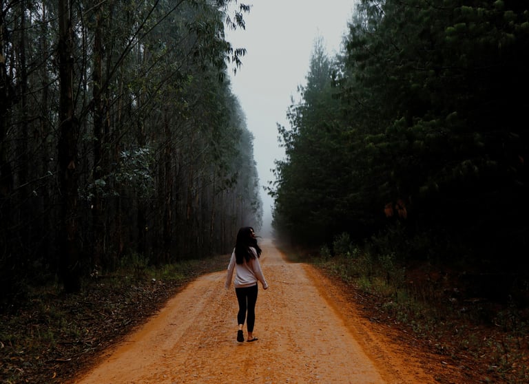 Brava Braun mindfully walking down a dirt road in the middle of a forest